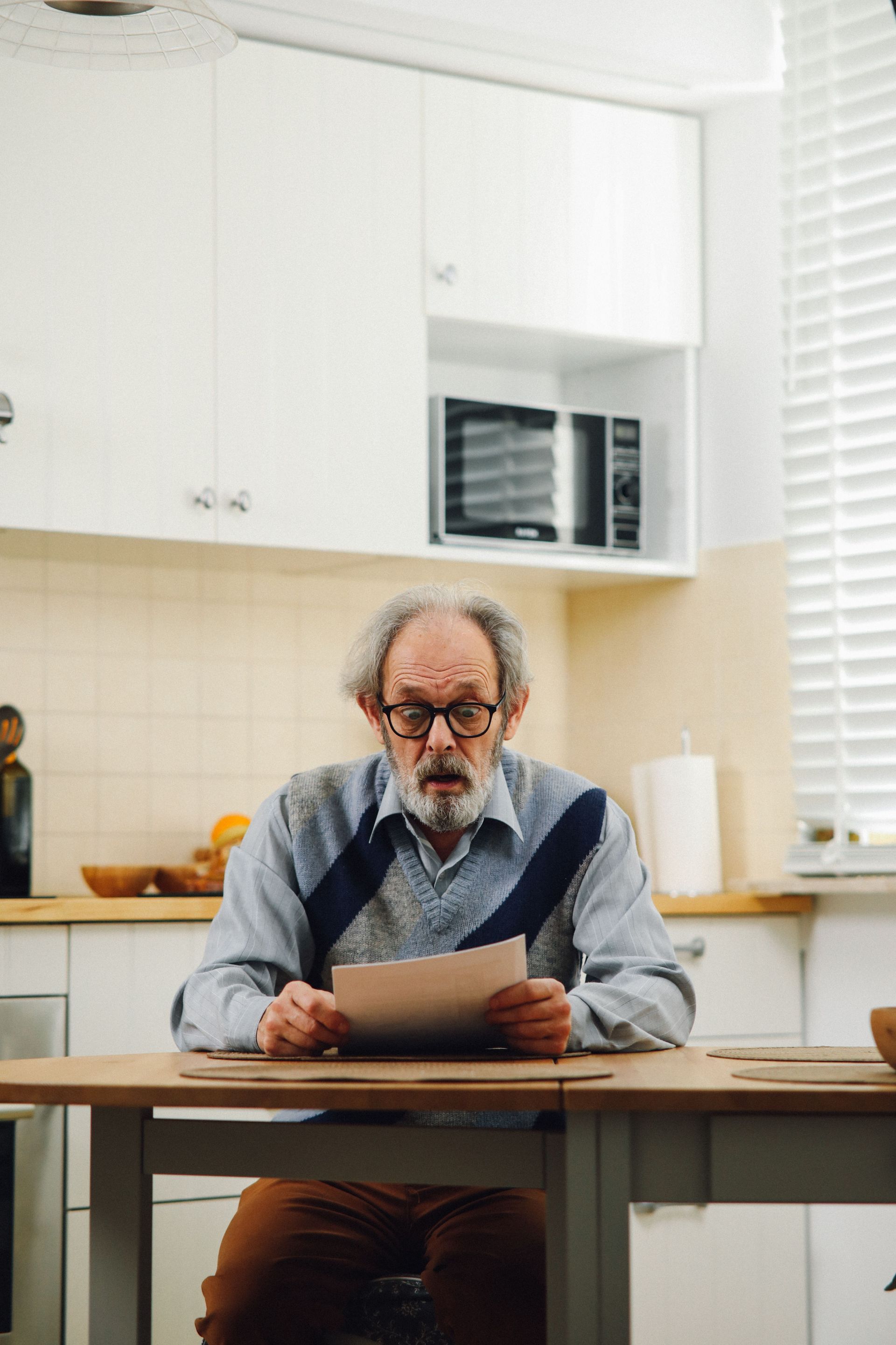 Homeowner reading an insurance non-renewal letter at a kitchen table in a North Texas brick ranch