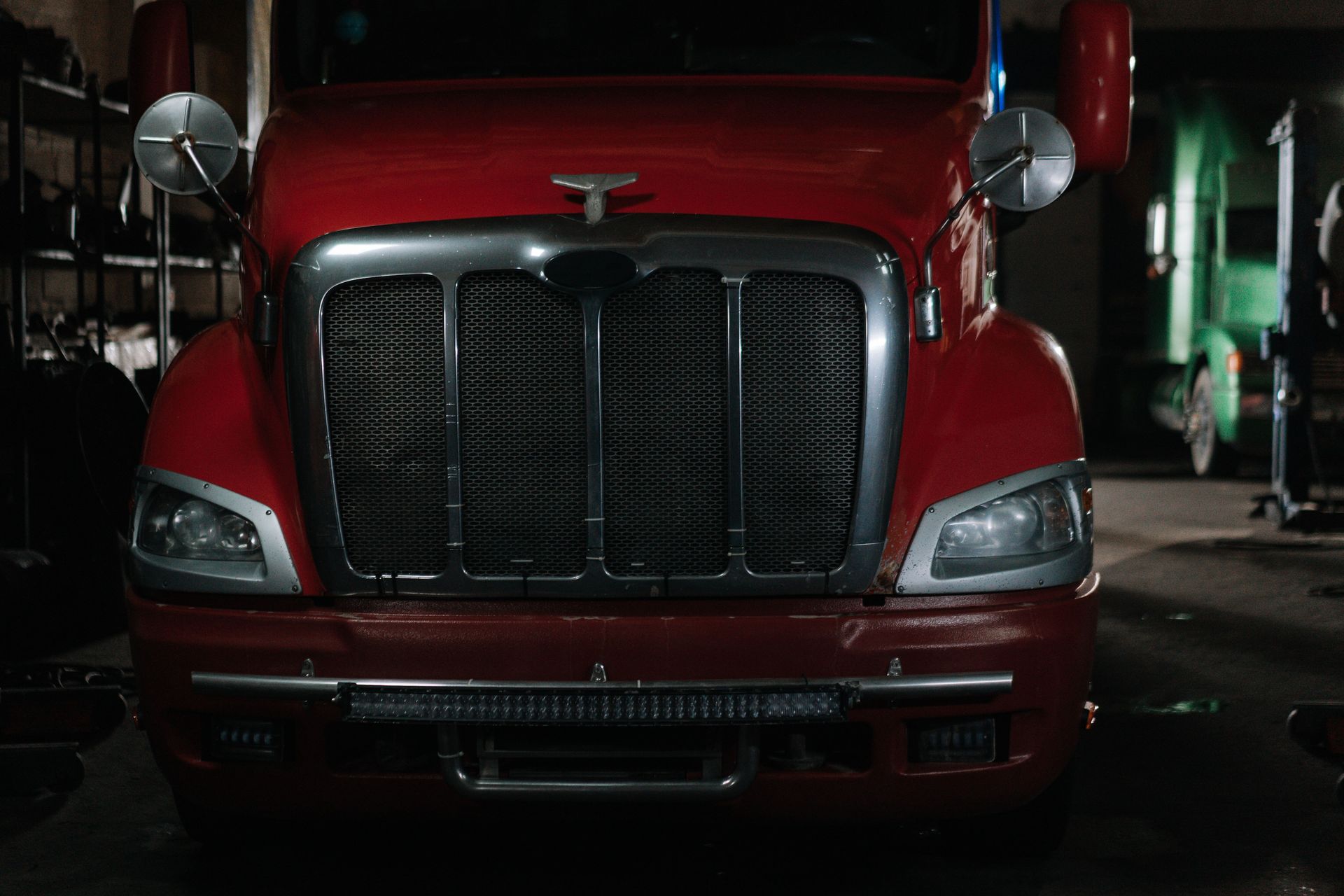 Red semi tractor parked inside a repair shop, the bill a liability-only policy will not pay