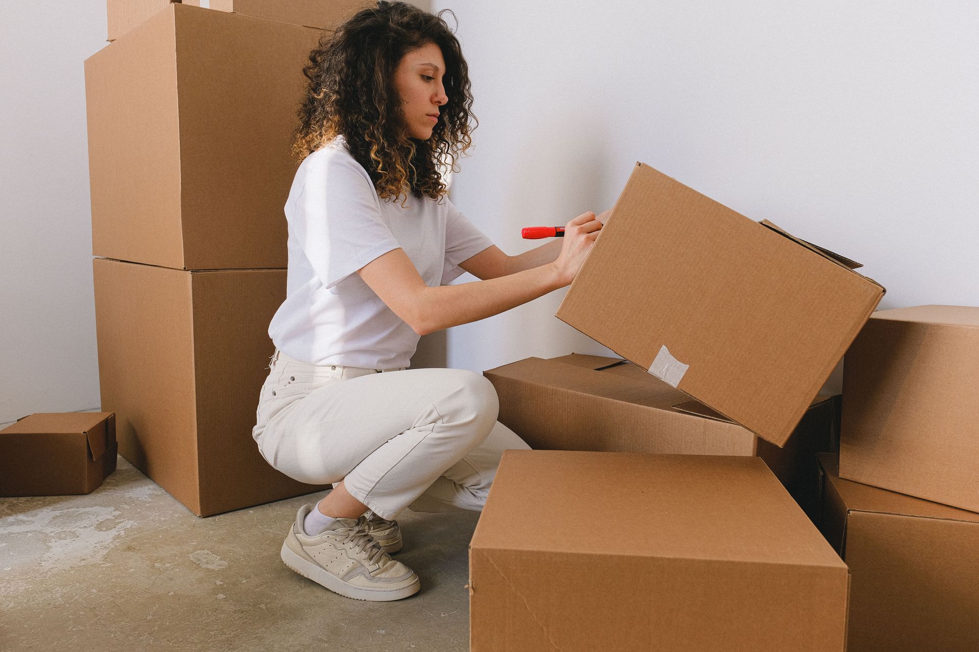 A home seller packing a shipping box surrounded by stacked inventory in her own living room