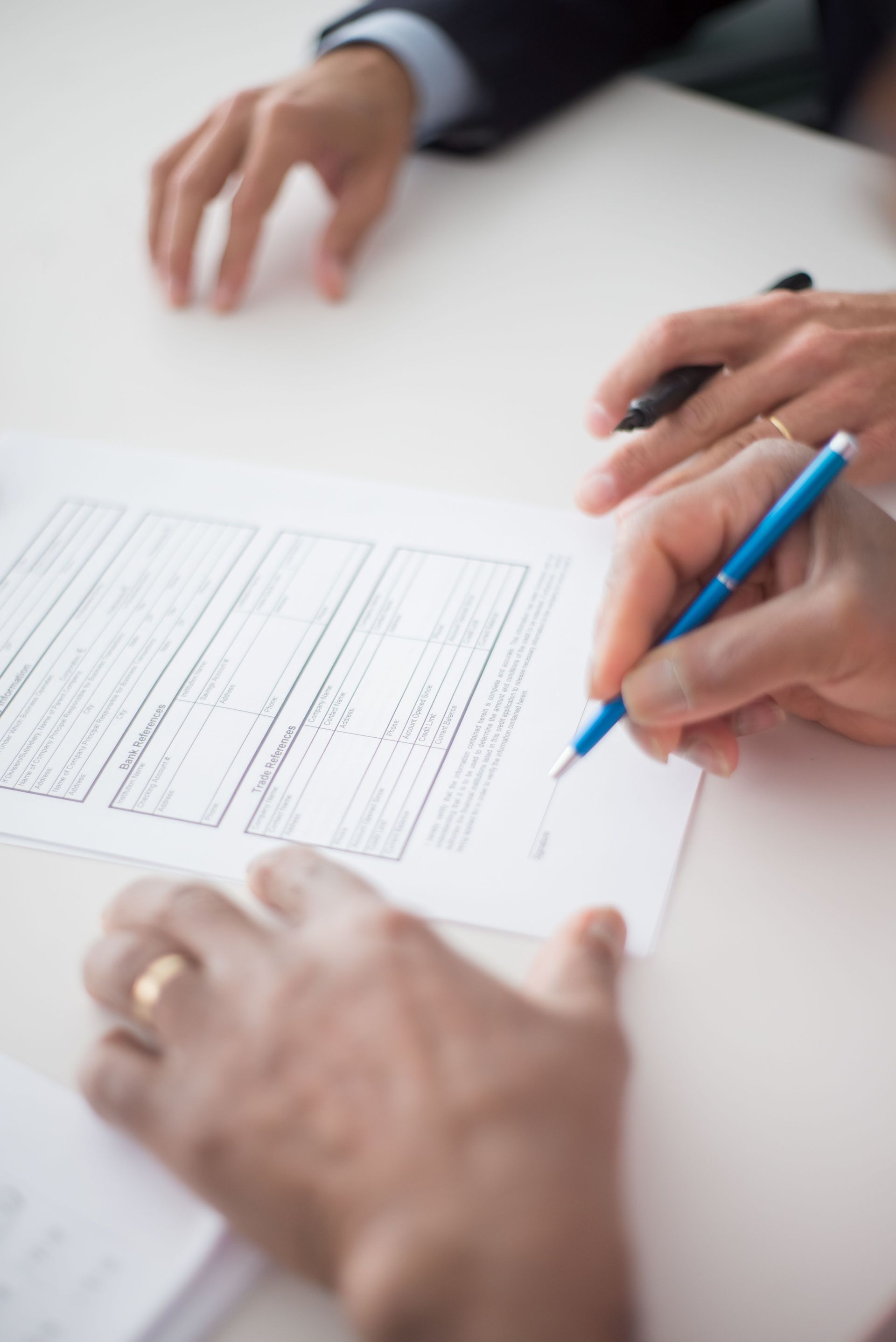 Close-up of a person completing official license paperwork with a blue pen at a desk before filing for a Texas ODL
