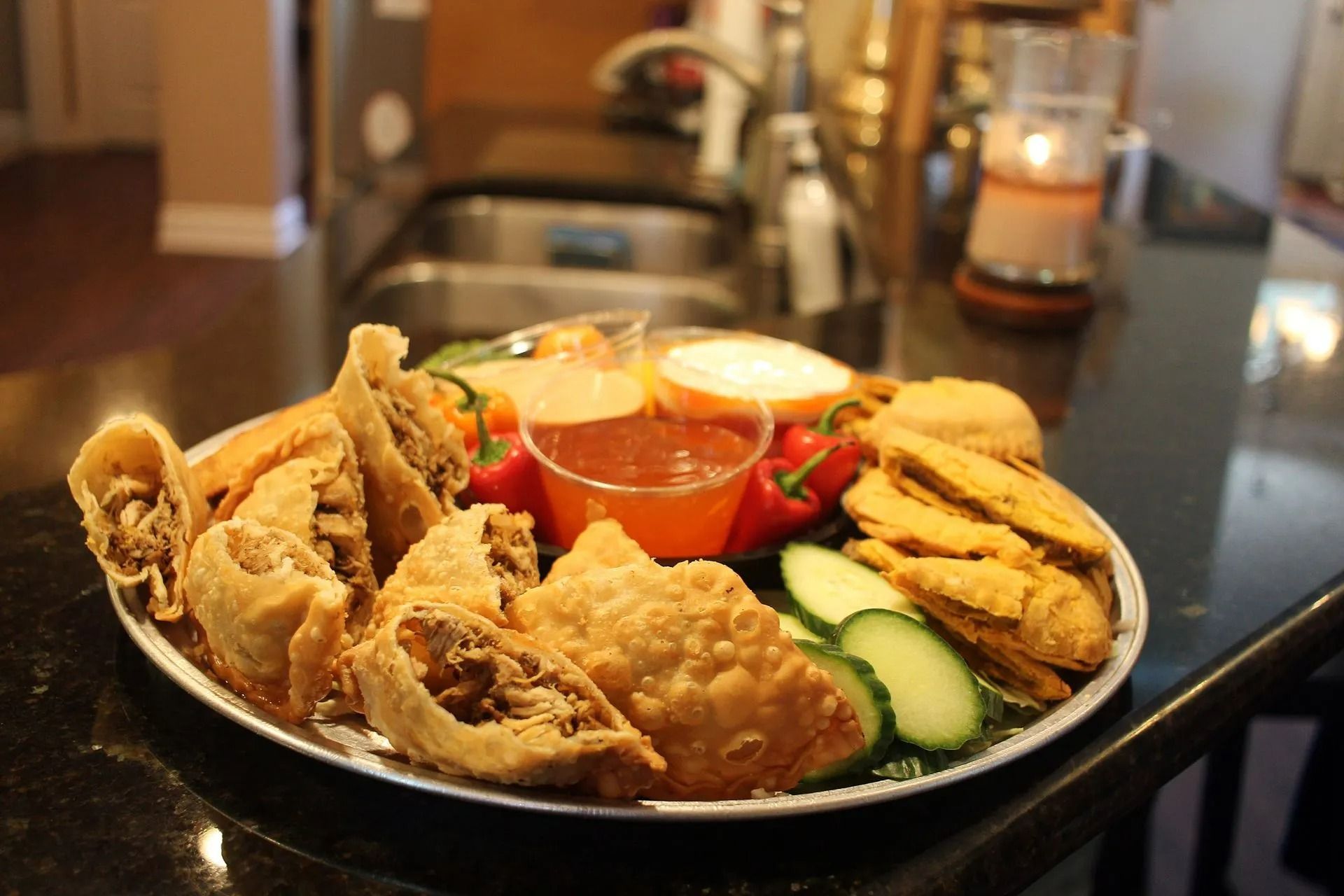 Appetizer platter with fried items, dipping sauces, and cucumber slices.