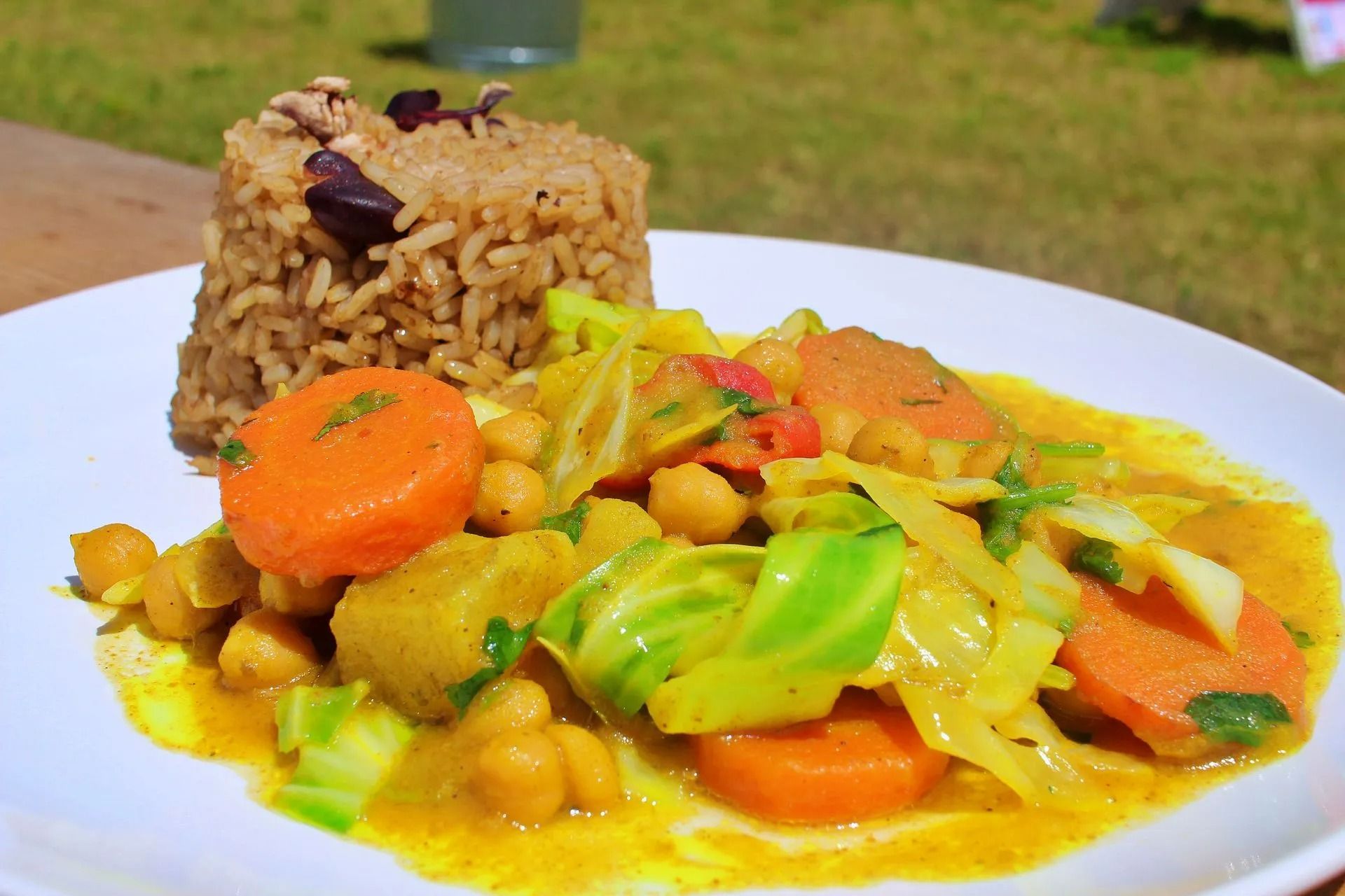 Plate of vegetable curry with carrots, cabbage, and chickpeas, served with brown rice.