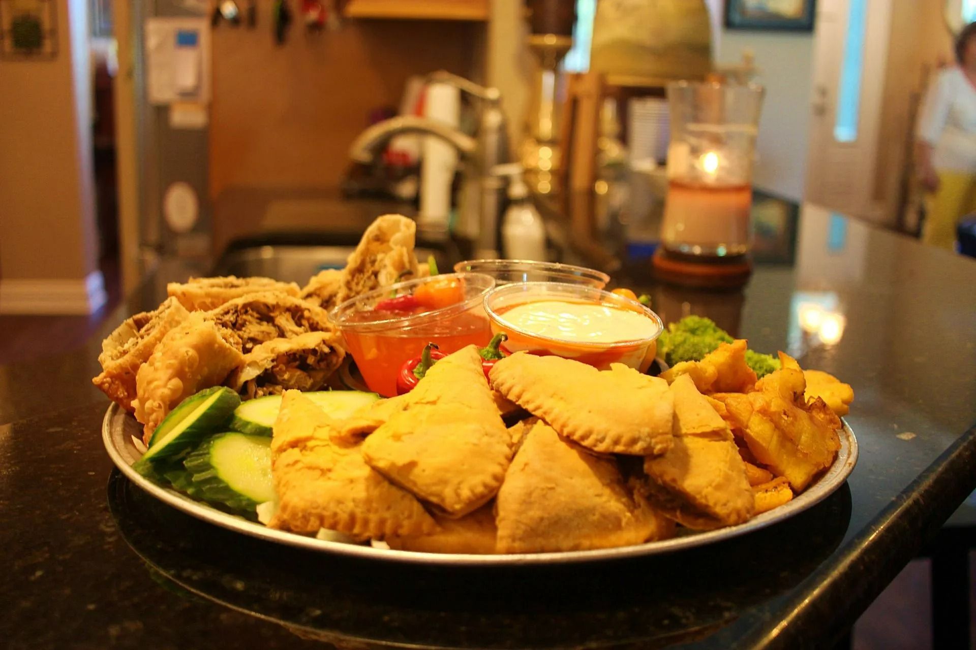 Tray of fried appetizers with dips, on a dark countertop.