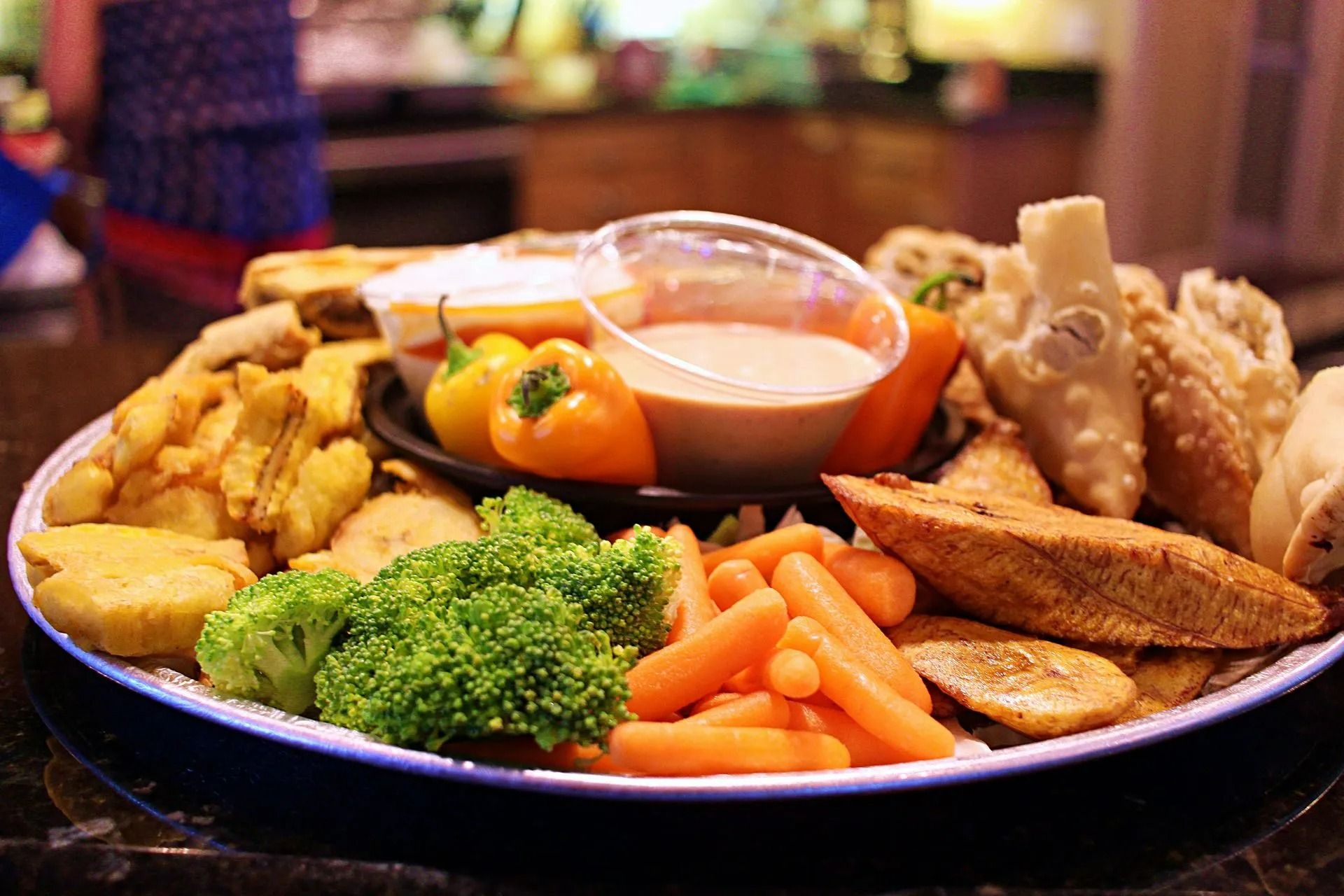 A platter of various fried foods and vegetables with dipping sauce.