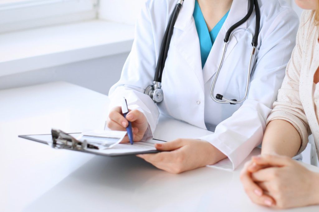 Doctor writing on clipboard during a consultation with a patient in a bright office
