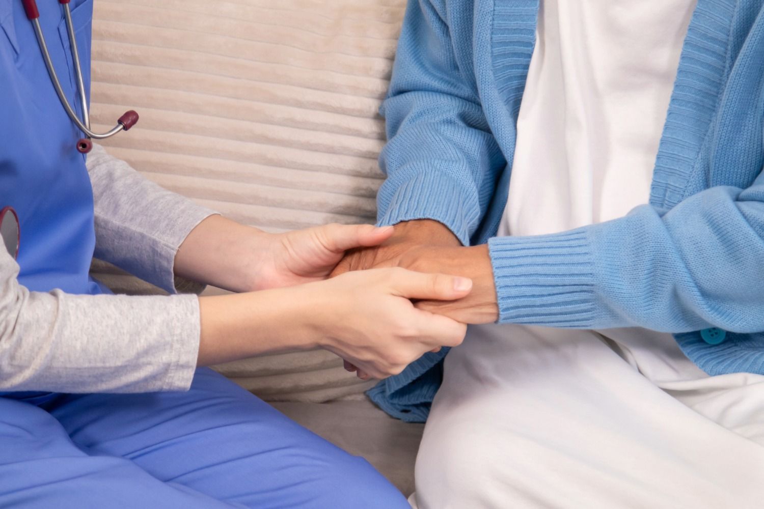 Two medical staff comforting a patient by holding hands in a clinic