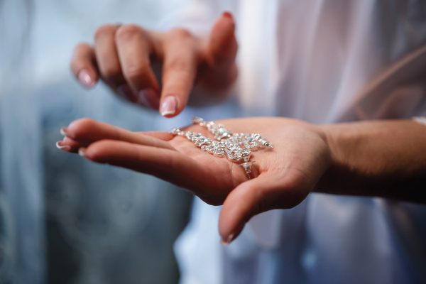 A woman is holding a necklace in her hand.