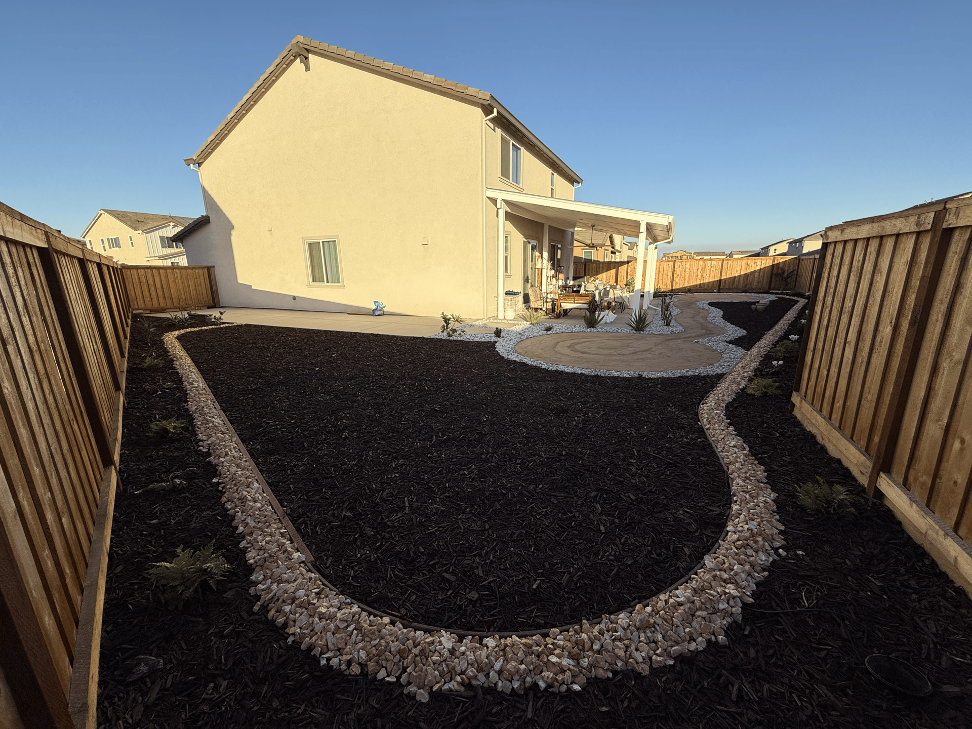 Backyard landscape design with mulch beds and decorative rock ground cover in Stockton CA