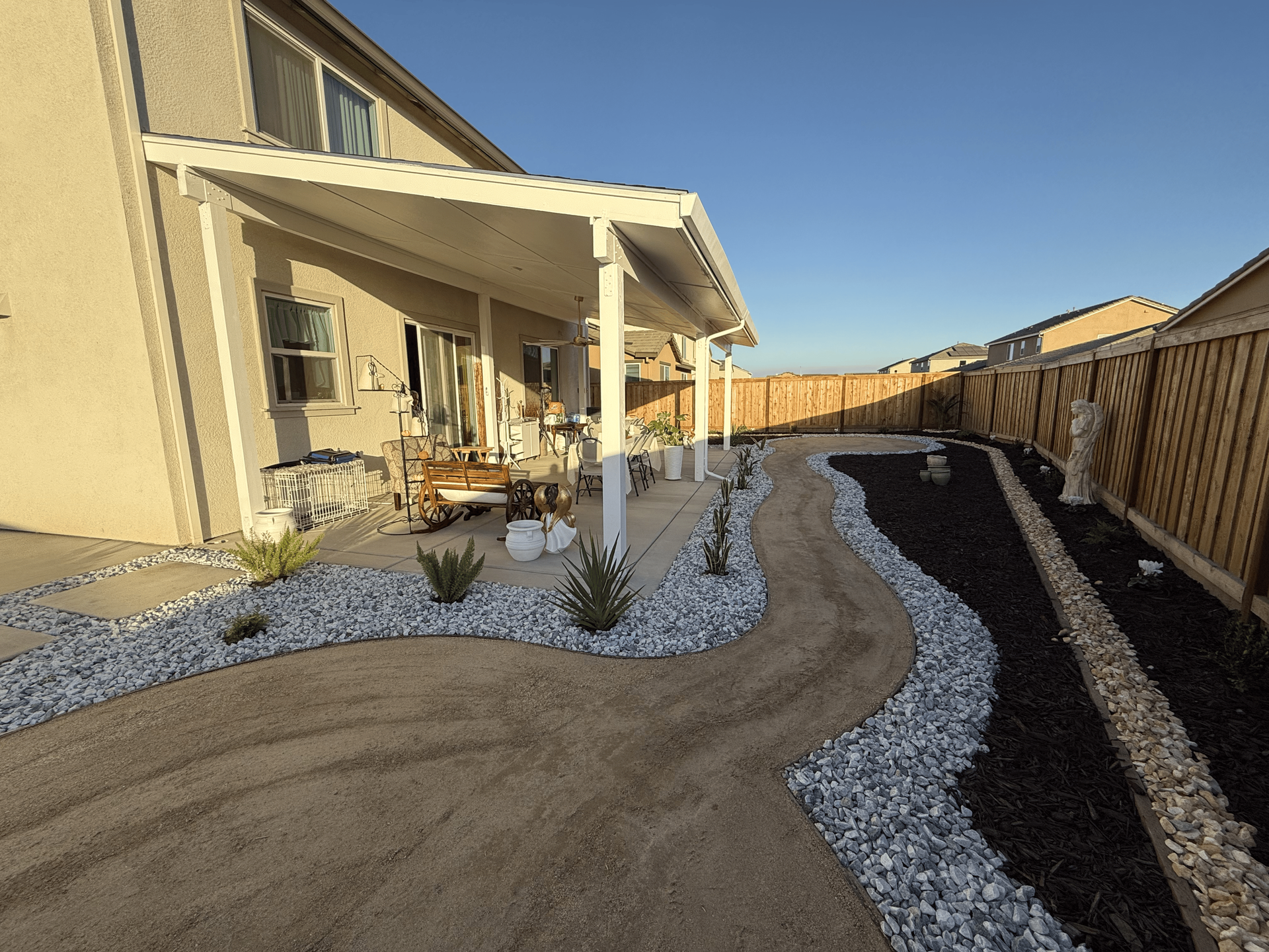 Decorative rock and mulch landscaping surrounding a backyard patio for clean, low-maintenance design