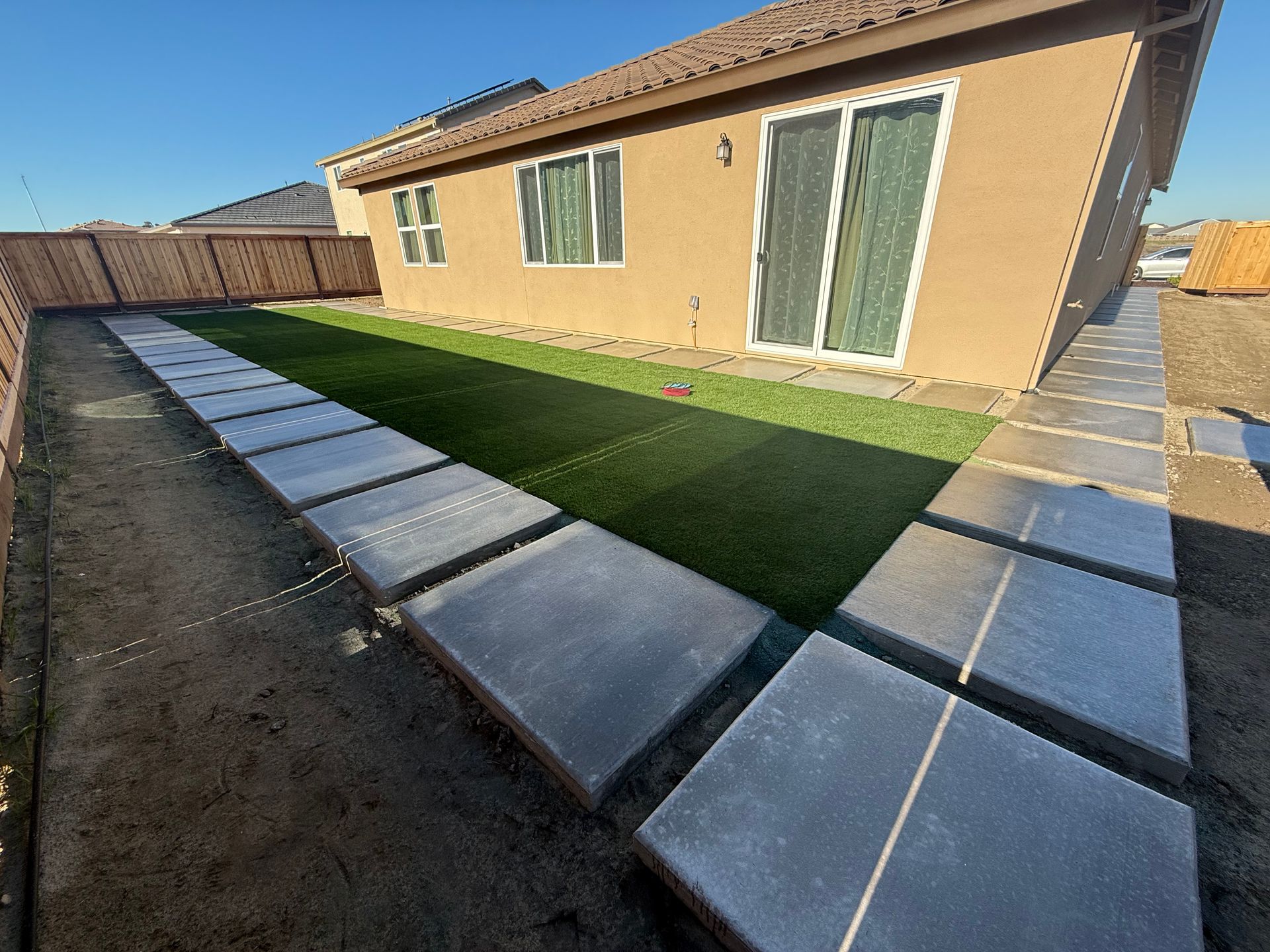 Turf and concrete walkway installed in a backyard patio in Ripon, CA