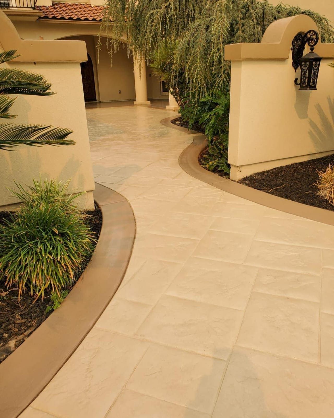 Stamped concrete driveway in Stockton with brick pattern and stone border.