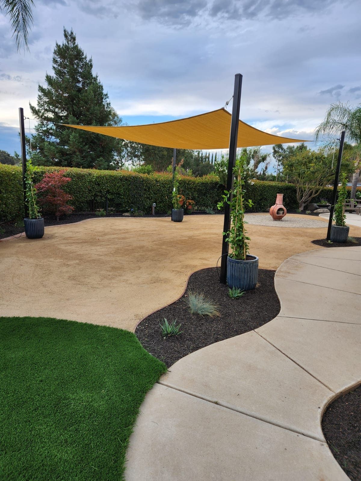 Shade structure installation in landscaped backyard Stockton.
