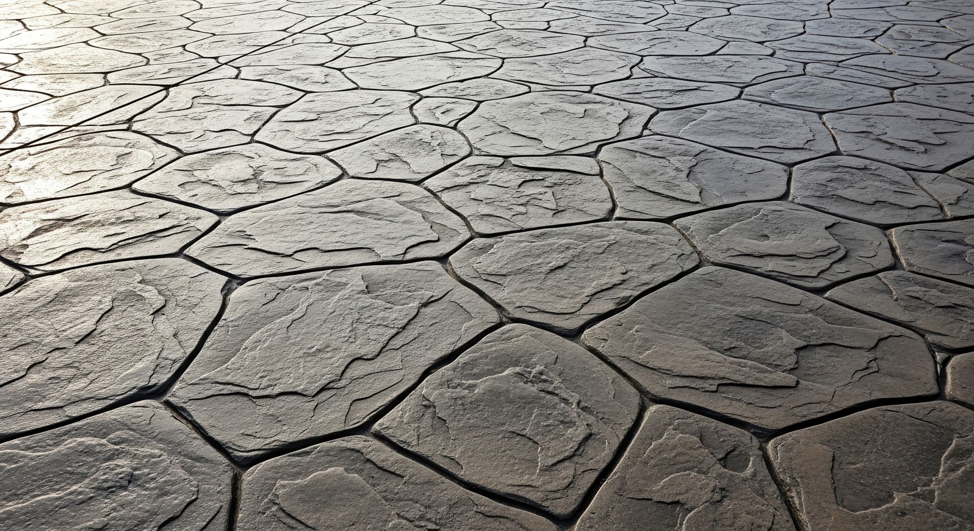 Textured concrete pavement with a cobblestone pattern in shades of gray.
