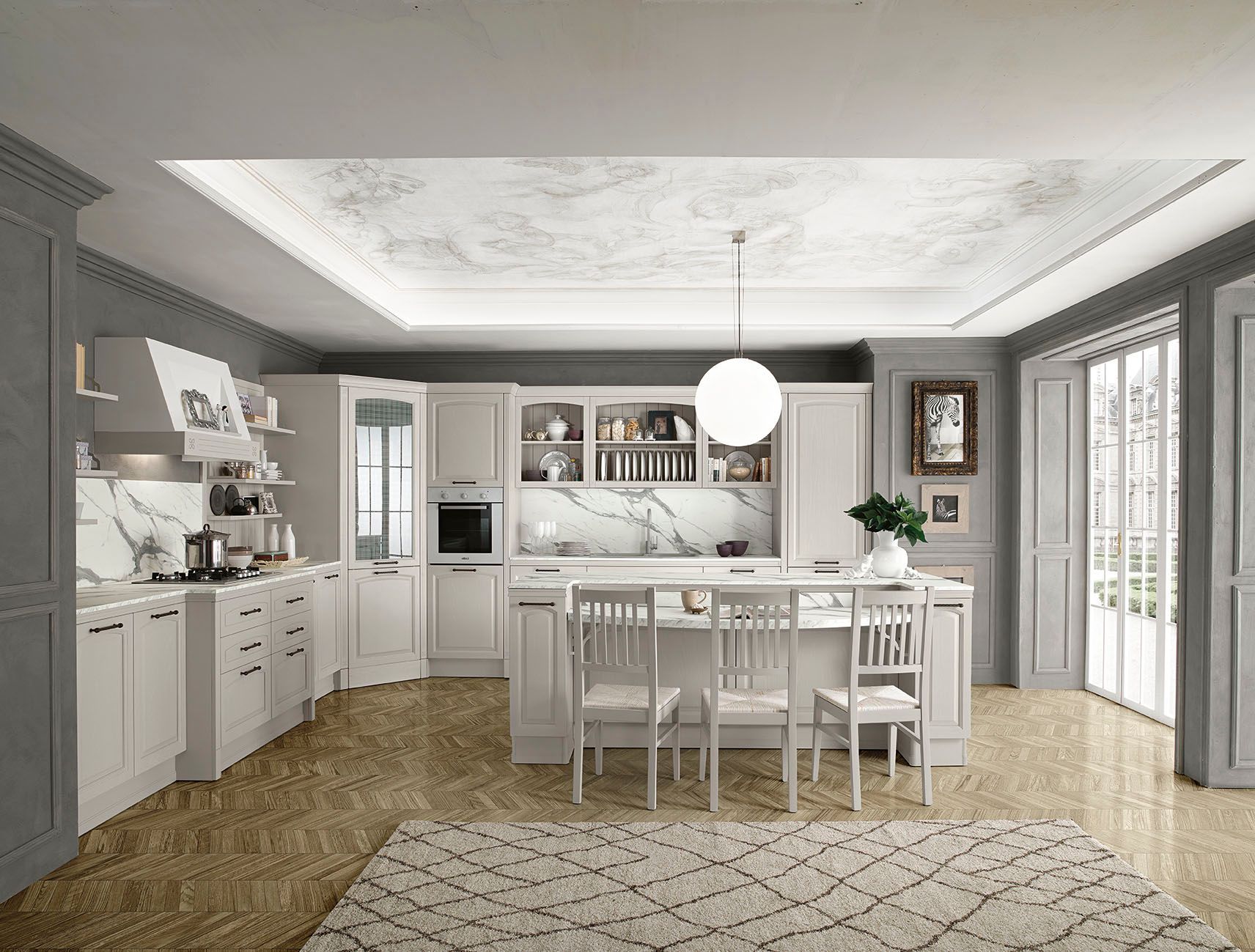 Cucina e sala da pranzo luminose e bianche con isola centrale, ampie finestre e tappeto a motivi geometrici.