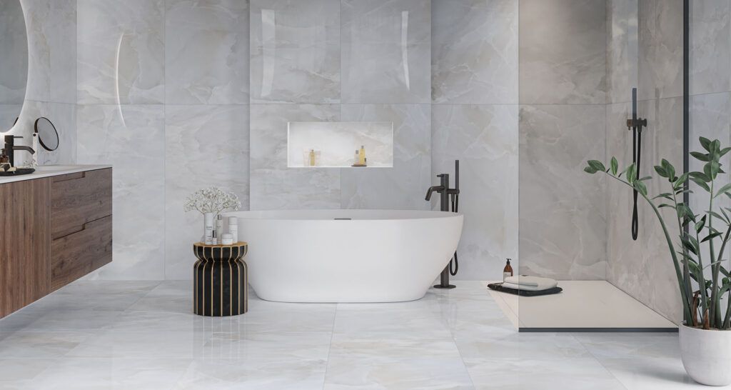 Bagno minimalista sui toni del grigio con vasca freestanding, nicchia a muro, mobiletto in legno e pianta in vaso.