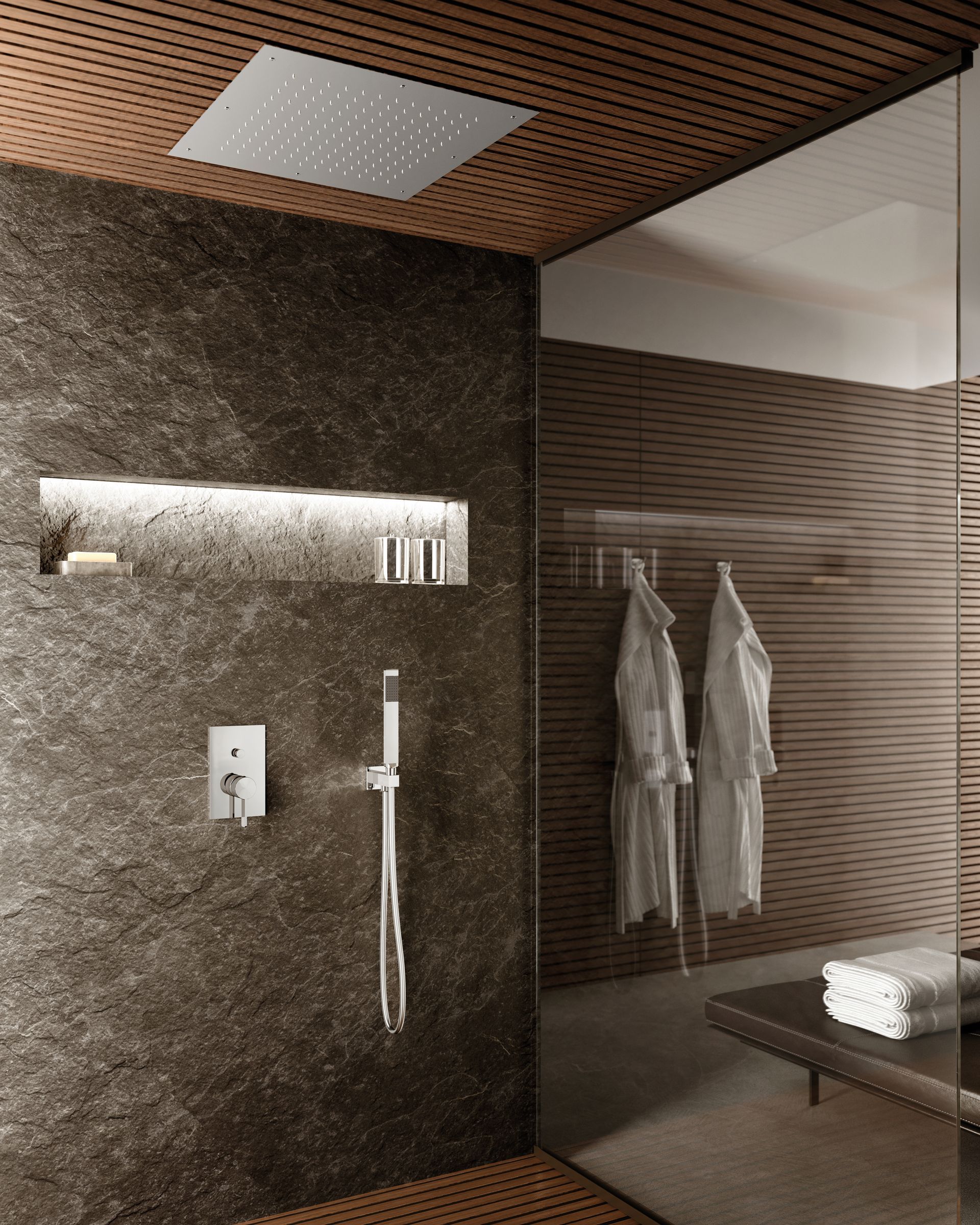 Doccia spa moderna con parete in pietra scura, soffione a pioggia e divisorio in vetro con accappatoi appesi.