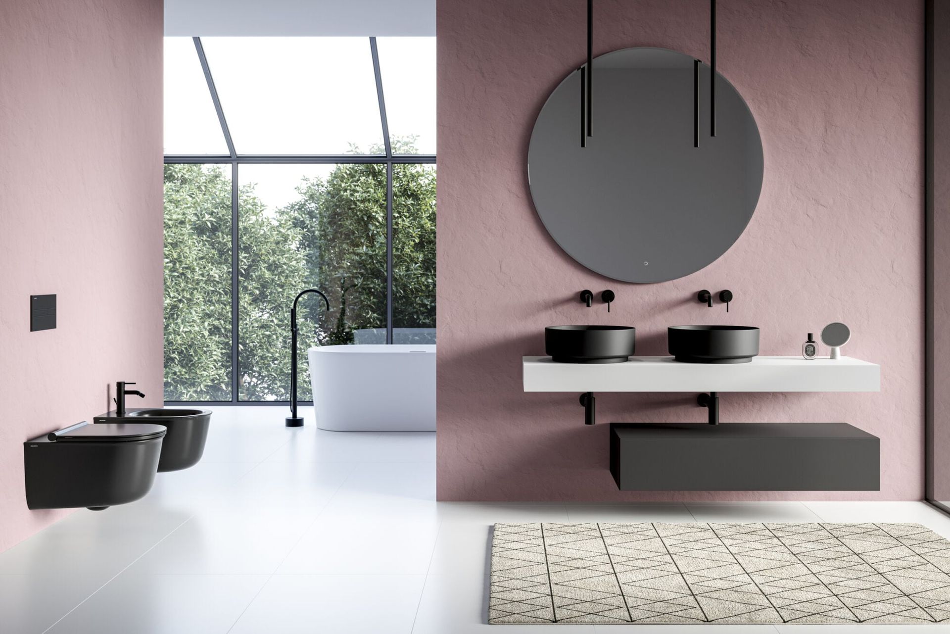 Mobile bagno moderno con specchio rotondo, parete rosa, rubinetteria nera e vasca freestanding accanto a grandi finestre.