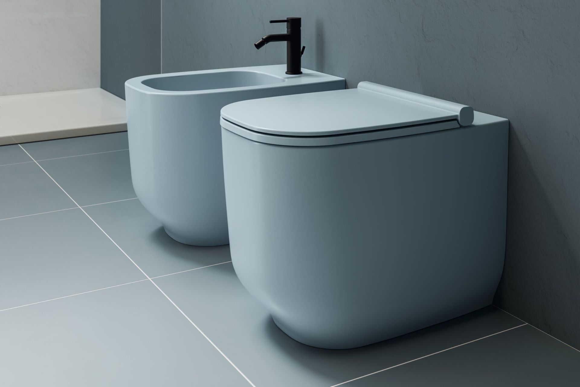 Due moderni bidet bianchi accanto a un rubinetto nero in un bagno piastrellato.