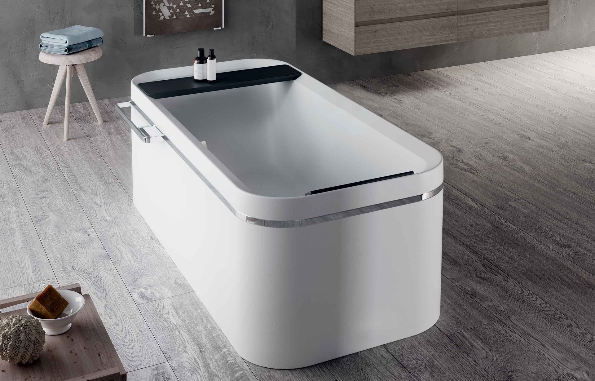 Vasca da bagno moderna bianca freestanding in un bagno minimalista con pavimento grigio e piccolo sgabello.