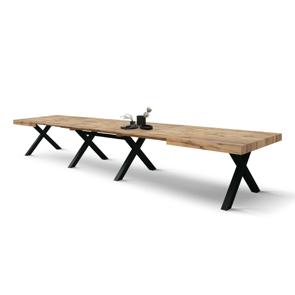Lungo tavolo da pranzo in legno con gambe in metallo nero a forma di X e un piccolo centrotavola, isolato su sfondo bianco.