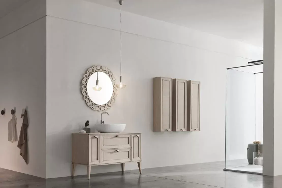 Corridoio minimalista bianco con specchio rotondo decorato, piccolo tavolino consolle e armadio alto con opere d'arte a parete.