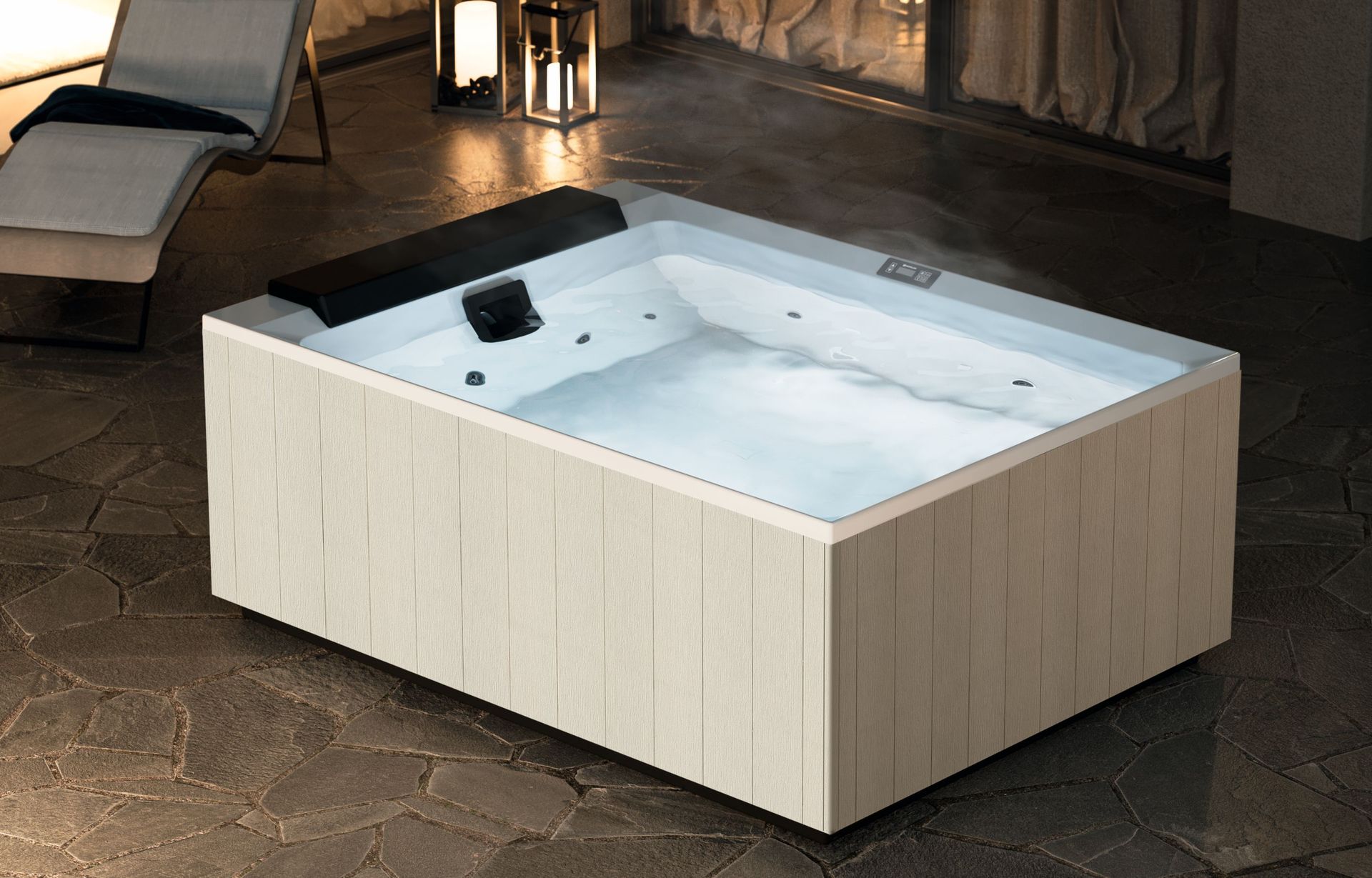 Vasca idromassaggio moderna, bianca e quadrata, con getti d'acqua, su un patio in pietra di notte.
