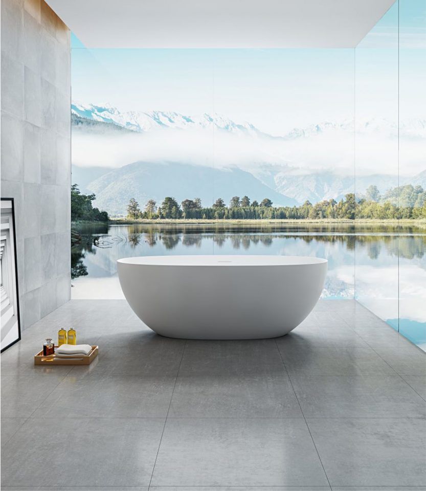 Bagno moderno e minimalista con vasca ovale bianca che si affaccia su un lago di montagna attraverso vetrate a tutta altezza.