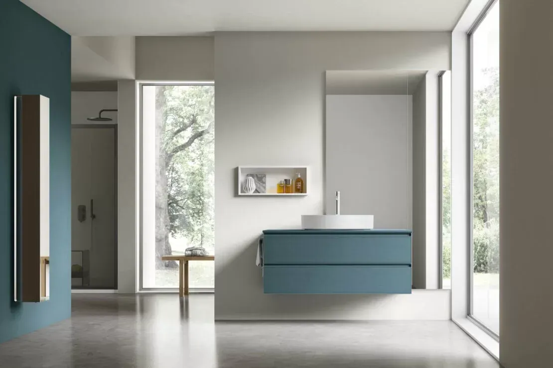 Bagno moderno con mobile lavabo blu, ampie finestre e pareti bianche minimaliste.