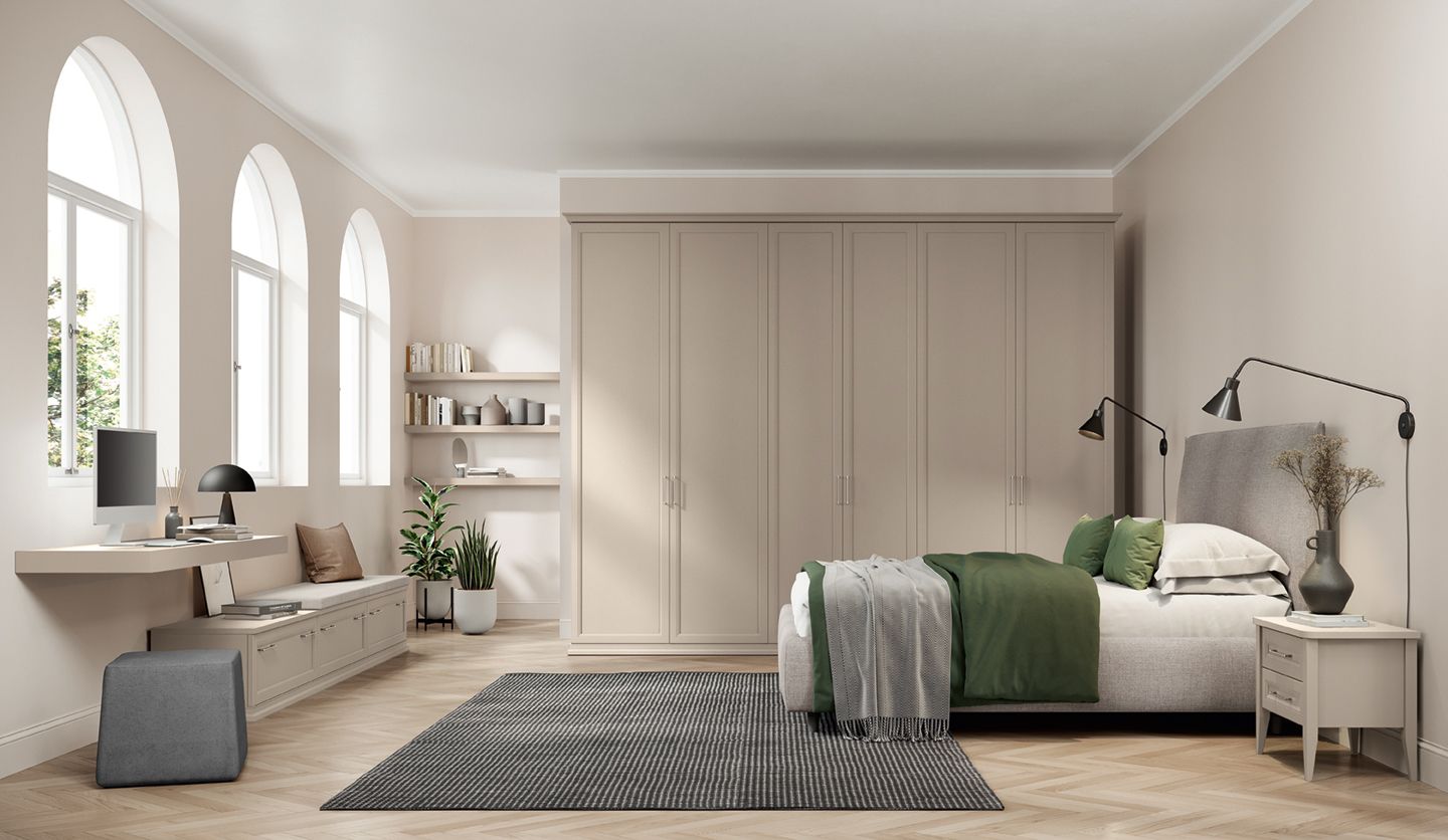 Camera da letto luminosa e minimalista con finestre ad arco, armadio beige, biancheria da letto verde e tappeto a motivi geometrici.