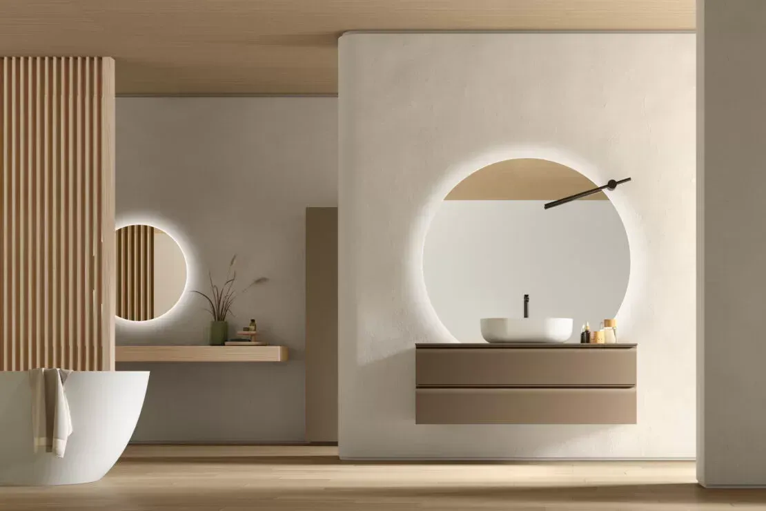 Bagno moderno sui toni del beige con specchio rotondo illuminato, mobile lavabo sospeso e parete divisoria a doghe di legno.
