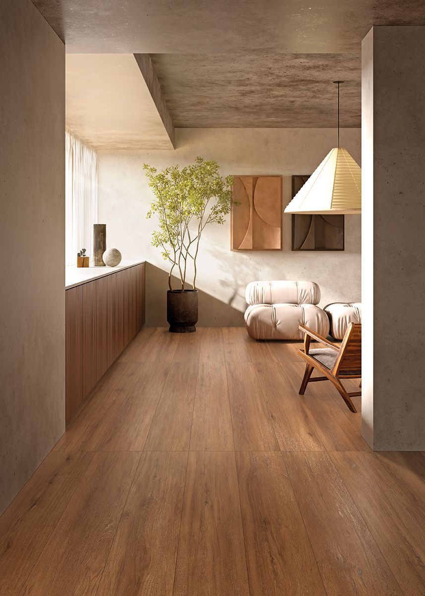 Soggiorno minimalista e luminoso con pavimento in legno, divano beige, pianta in vaso e lampada a sospensione.