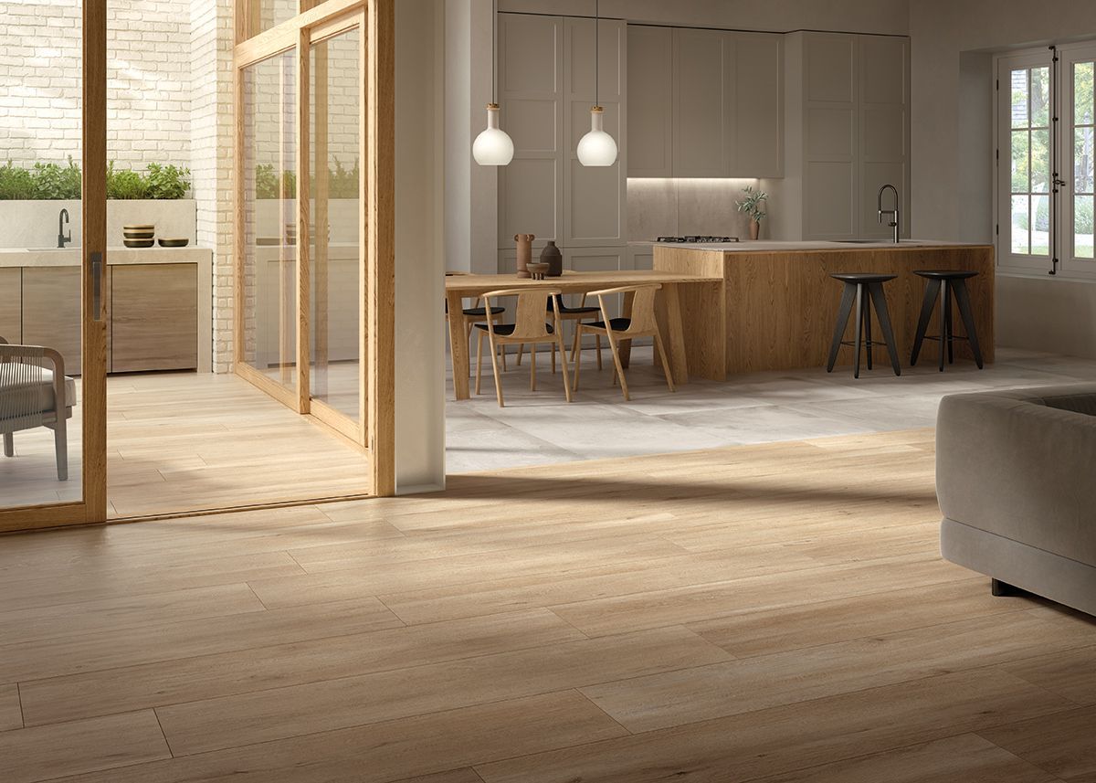 Cucina e zona pranzo luminose e moderne con pavimenti in legno, isola con posti a sedere e lampade a sospensione.
