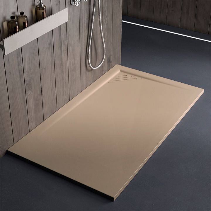 Piatto doccia beige accanto a una parete in legno in un bagno moderno.