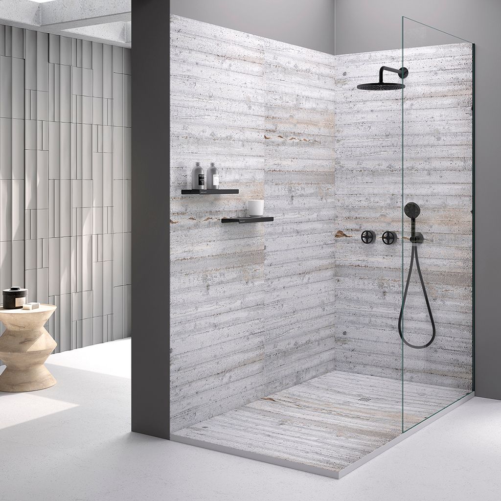 Moderna cabina doccia con pareti in pietra bianca, rubinetteria nera e divisorio in vetro in un bagno luminoso.