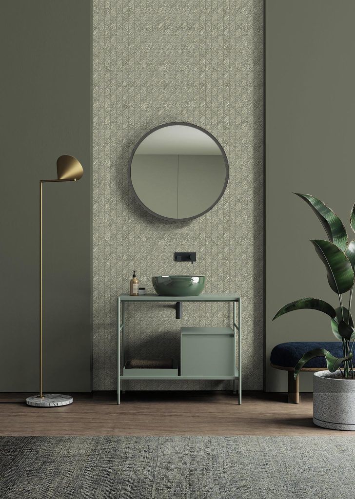 Elegante soggiorno con specchio rotondo, consolle, lampada da terra e piante in vaso su pareti con finitura materica.