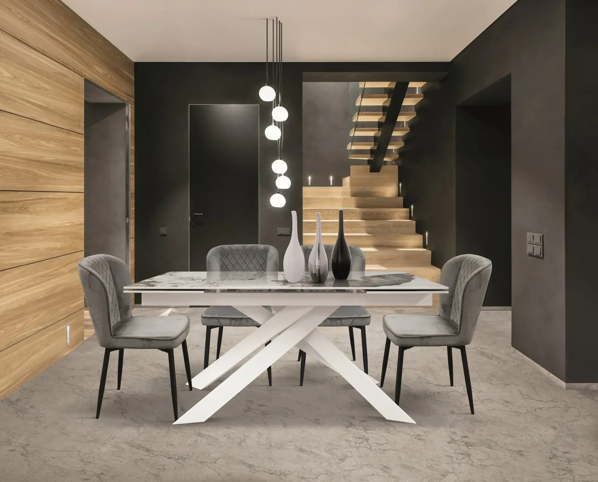 Sala da pranzo moderna con sedie grigie, tavolo bianco, pareti nere e scala in legno.