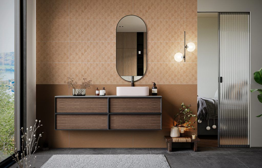 Mobile bagno moderno con mobiletto in legno, specchio ovale, parete rivestita con piastrelle beige e porta doccia in vetro satinato.
