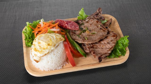 Rice plate with fried egg, sliced beef, and vegetables on a wooden tray