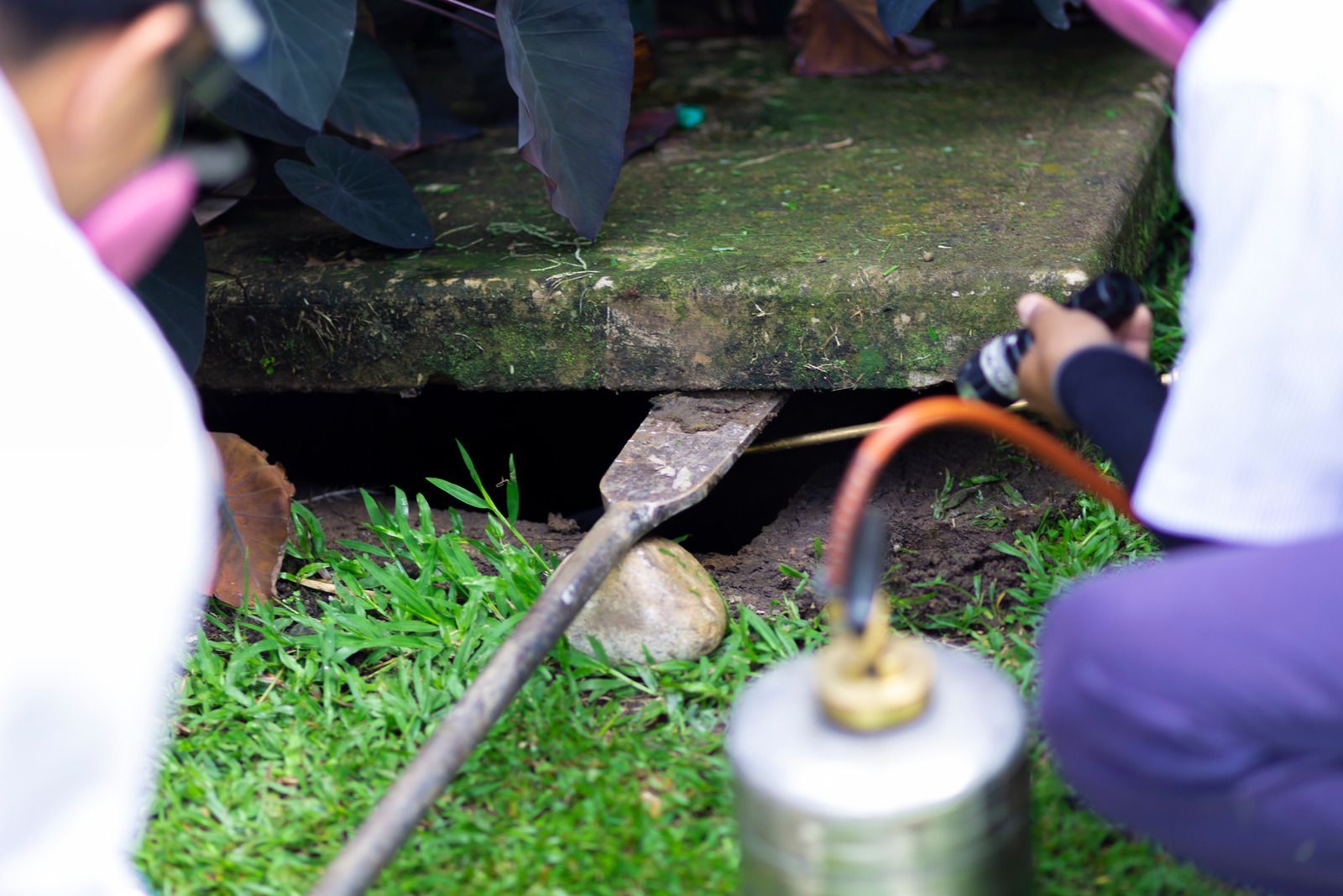 A group of people are working on a drain with a torch.
