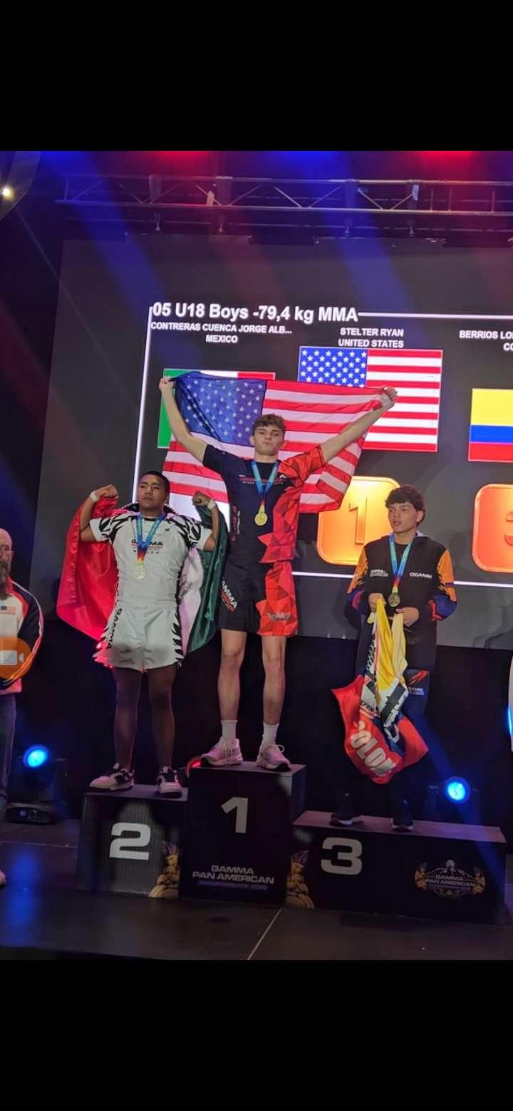 Three athletes on a podium holding medals and flags at a sports award ceremony