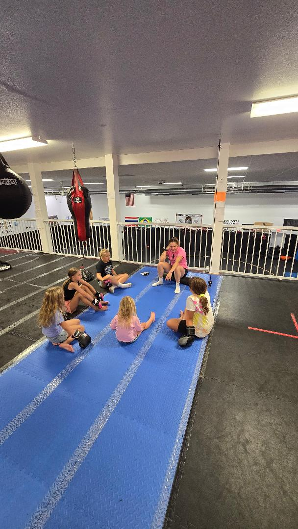 Children doing floor exercises on blue mats in a gym studio