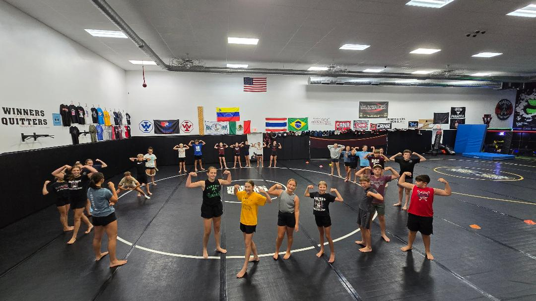 People standing in a gym in rows, raising their hands during a group exercise class.