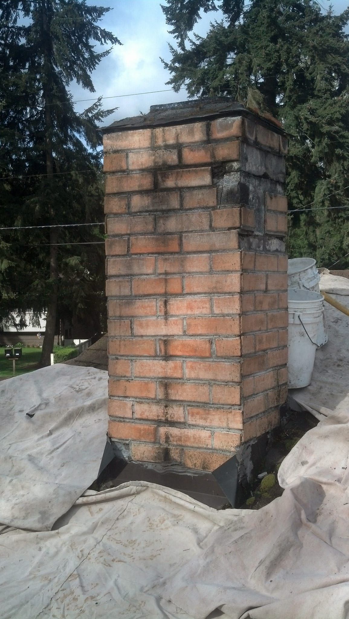 A brick chimney is sitting on top of a roof.