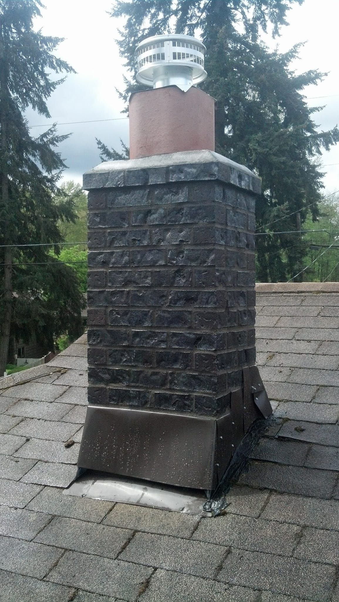 A brick chimney is on the roof of a house