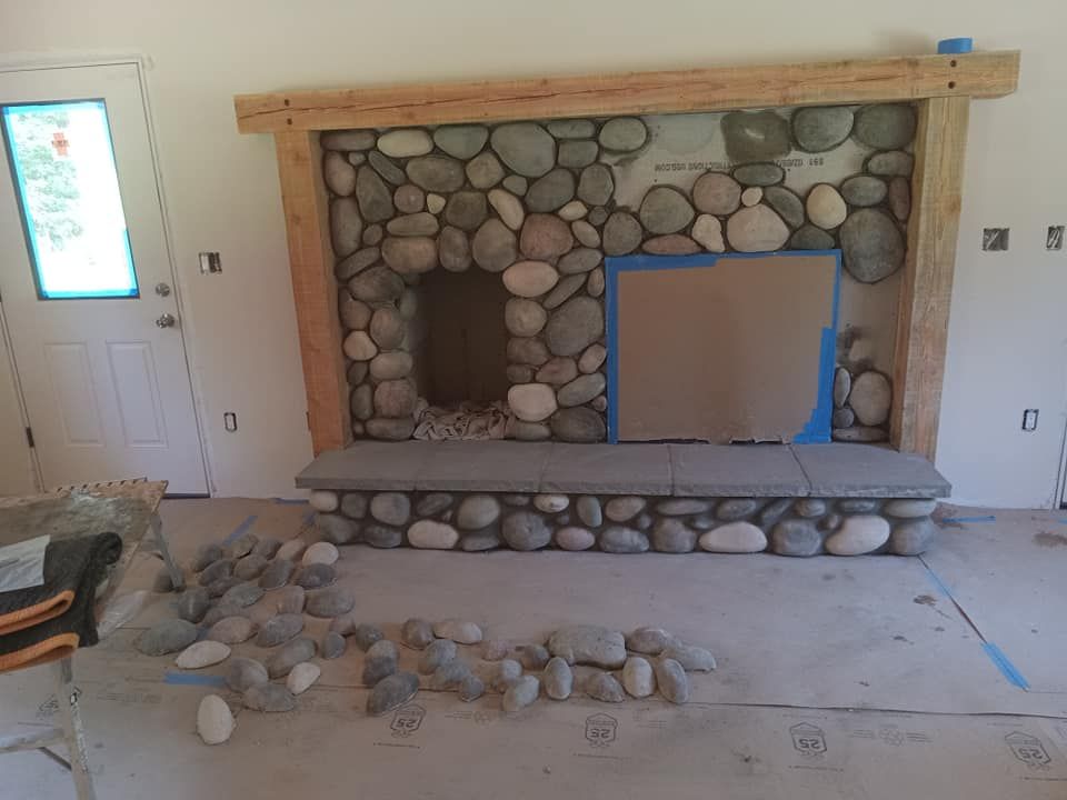 A stone fireplace is being built in a living room.