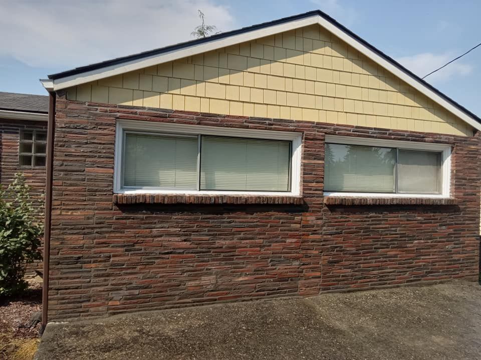 A brick house with two windows and a yellow roof