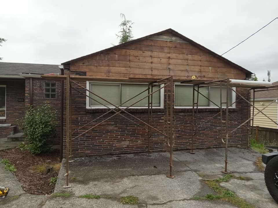 A brick building with scaffolding around it and a car parked in front of it.