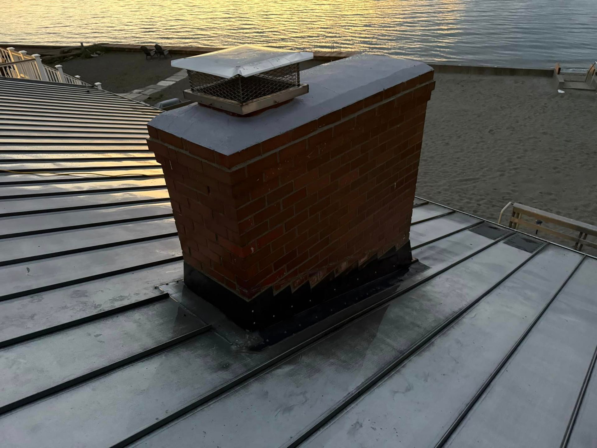 A brick chimney on top of a metal roof