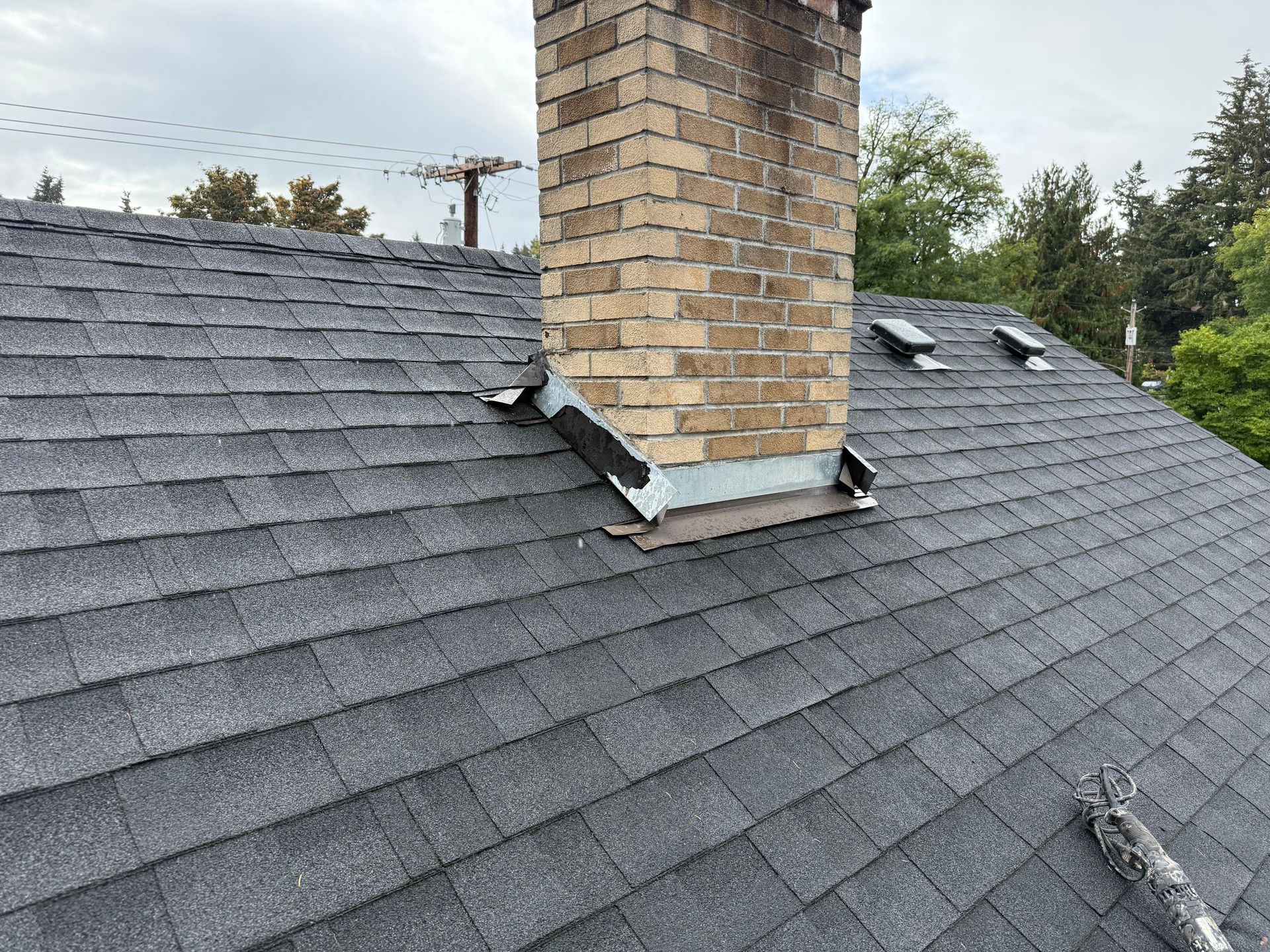 A man is working on a chimney on the roof of a house