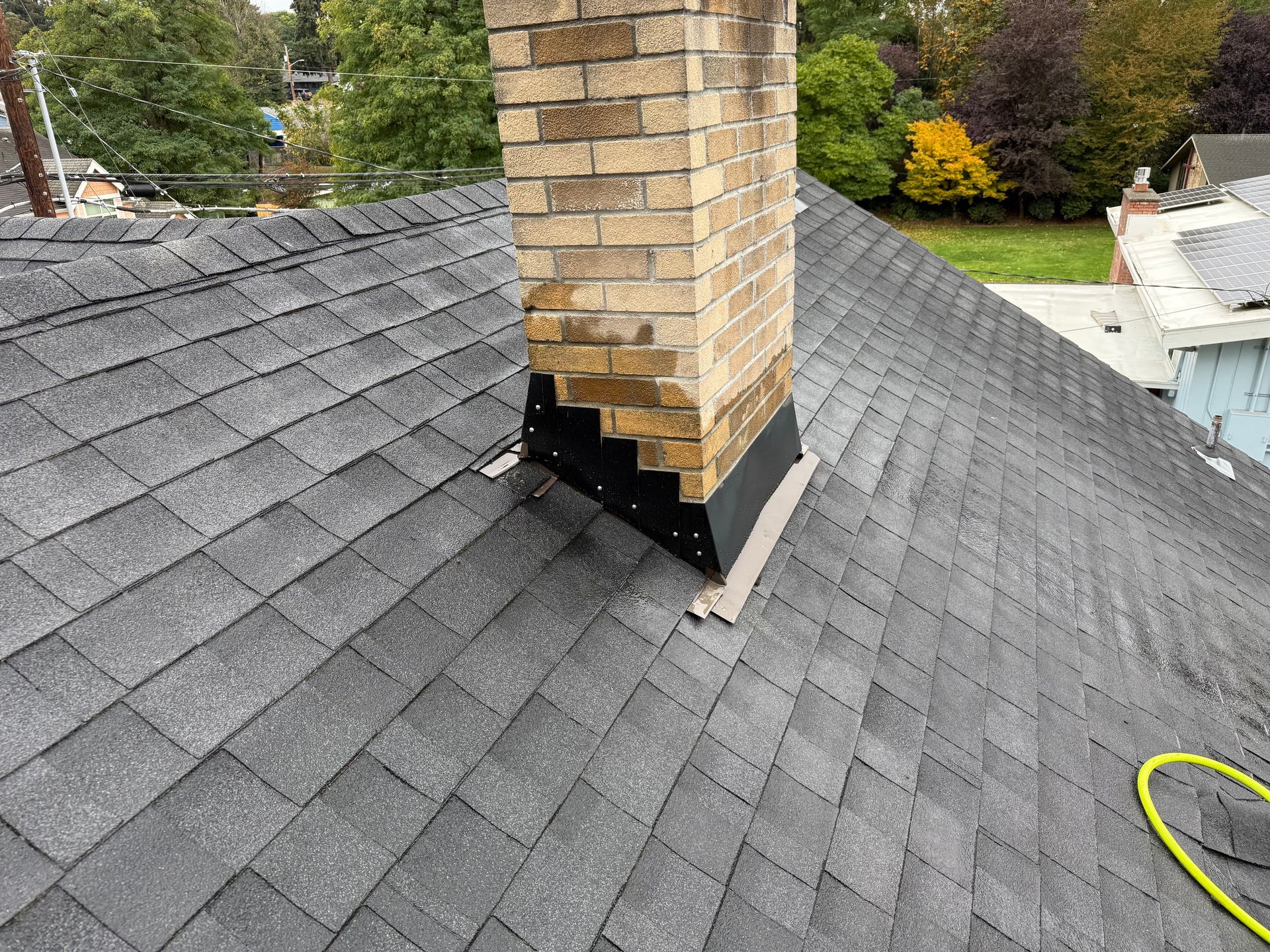 A brick chimney is on the roof of a house